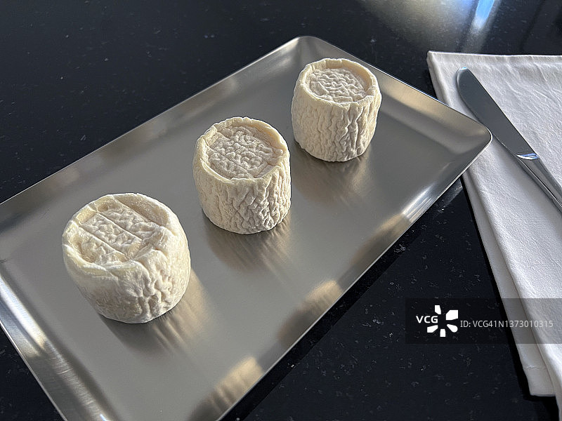 黑色背景银盘中的三块山羊奶酪图片素材