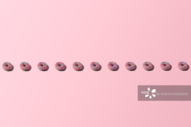 粉色背景上的甜甜圈直线排列图片素材