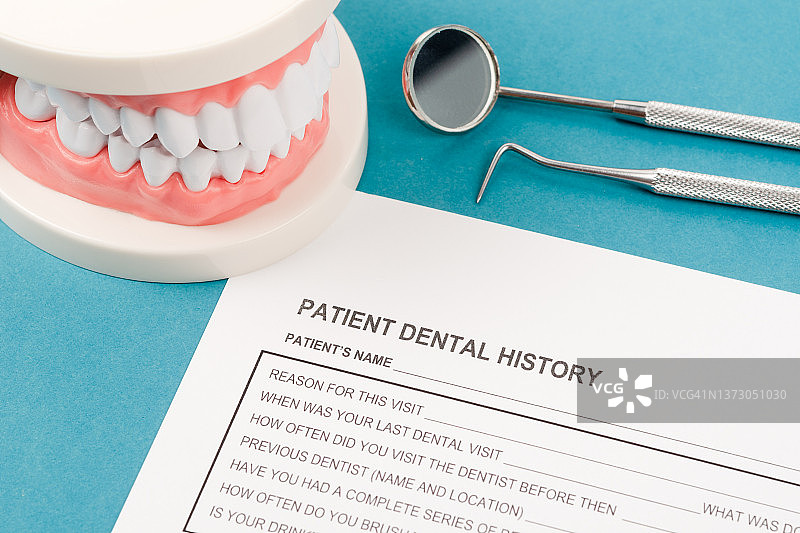 一套金属牙医医疗设备工具，诊所蓝色背景上的牙齿模型图片素材