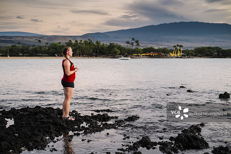 一名女子在夏威夷大岛的岩石海岸线上观看日落图片素材