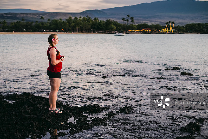 一名女子在夏威夷大岛的岩石海岸线上观看日落图片素材