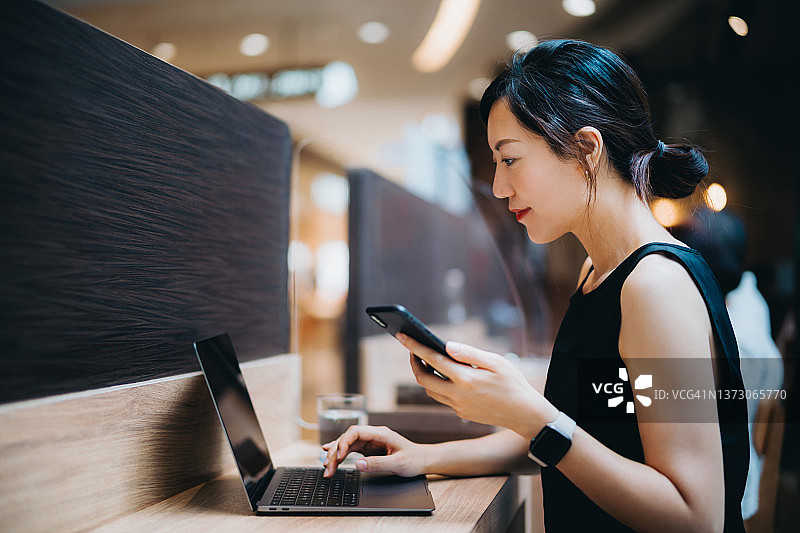自信的亚洲女商人使用智能手机和笔记本电脑在共享办公空间工作，与商业伙伴合作，自由职业者，运营小企业，自主创业理念图片素材