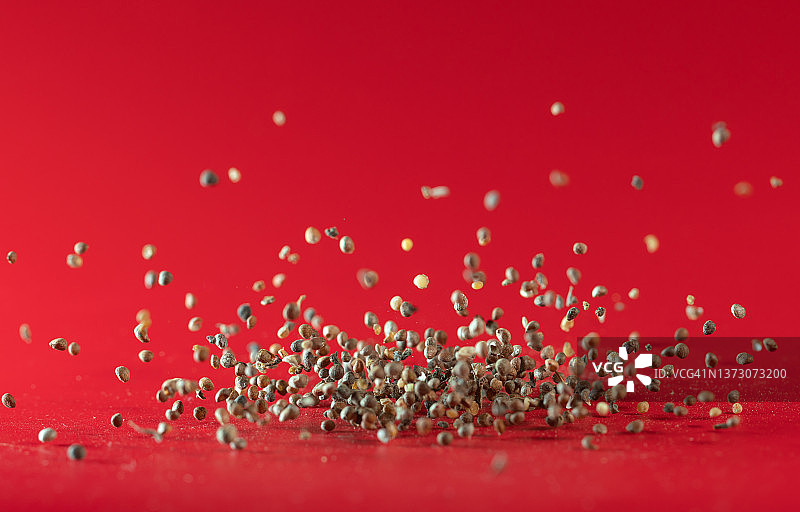 在红色背景中飞舞的紫色紫苏籽图片素材