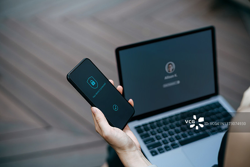 年轻女人坐在城市办公园区长椅上在户外工作，登录到她的笔记本电脑并用手握着智能手机的裁剪照片特写图片素材