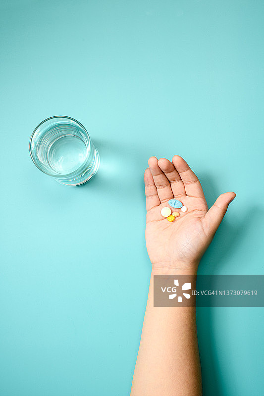 儿童手掌上的医疗药丸和一杯水图片素材