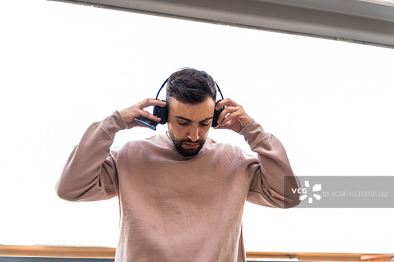 男人戴着无线耳机，拿着手机图片素材