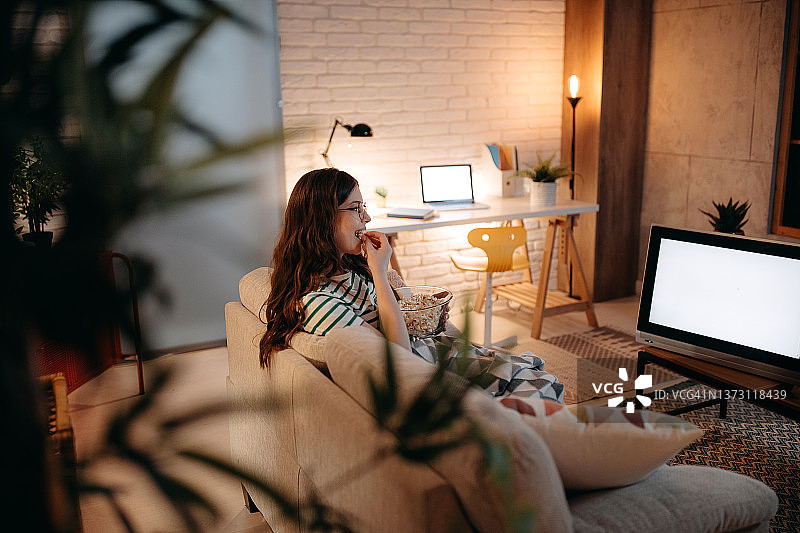 女人晚上在沙发上看电视图片素材