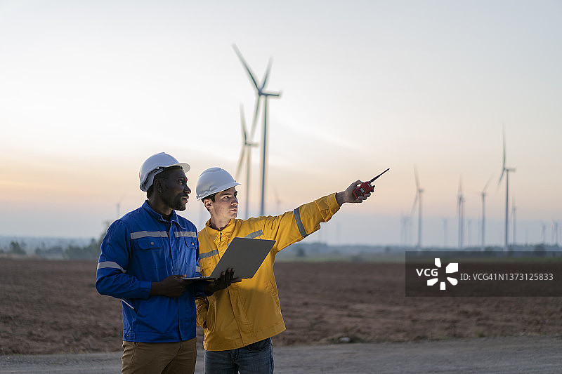 两位工程师讨论风力涡轮机维护计划并检查风向图片素材