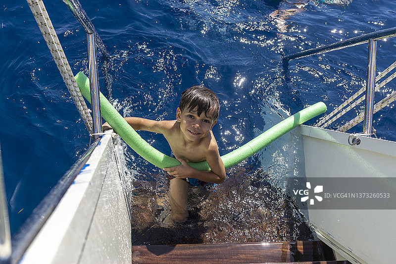 在游艇台阶上学习游泳的男孩图片素材