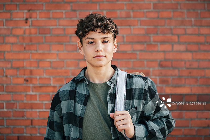 站在砖墙前的青少年男孩肖像图片素材