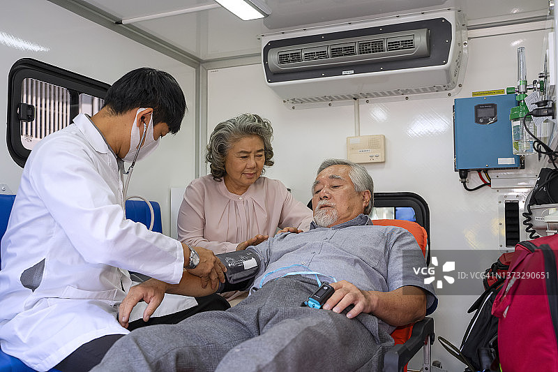 医生在救护车上为病人检查，病人妻子陪同图片素材