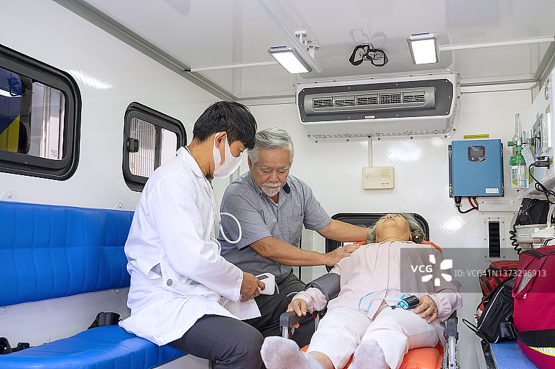 医生在救护车上为病人检查，病人妻子陪同图片素材