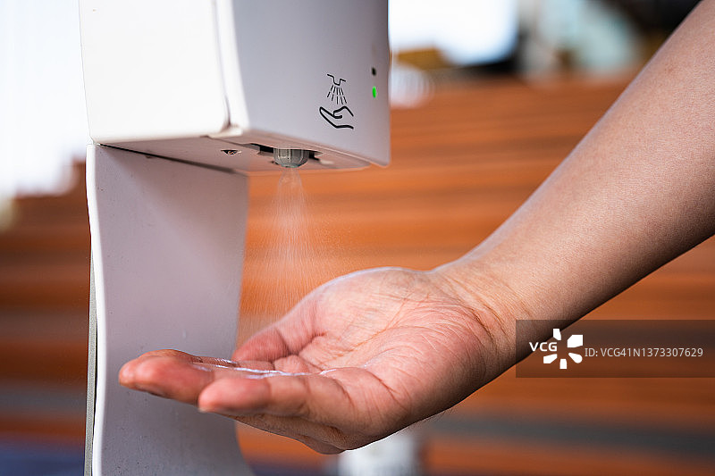人手使用自动洗手液分配器图片素材