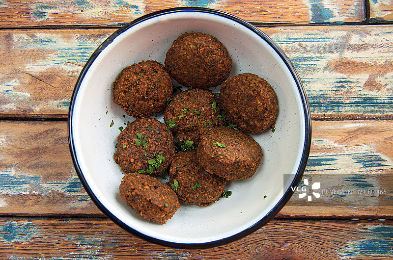 旧木桌上搪瓷碗中的熟沙拉三明治球图片素材