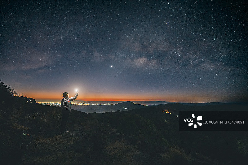 夜晚，男人拿着灯笼，背景是银河系图片素材