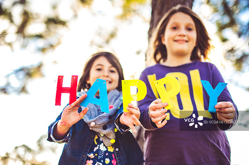可爱微笑的孩子们举起字母，拼出“快乐”，充满喜悦和友谊图片素材
