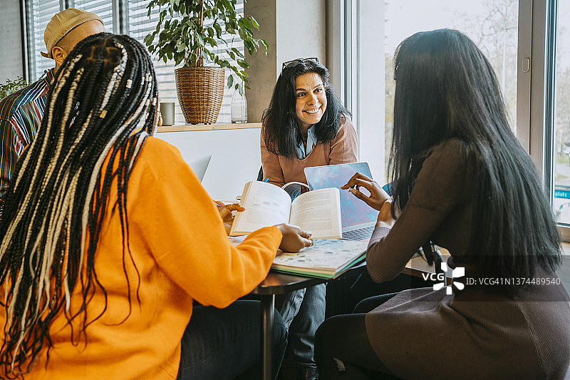 笑容满面的中年女学生在大学自助餐厅与朋友们讨论图片素材