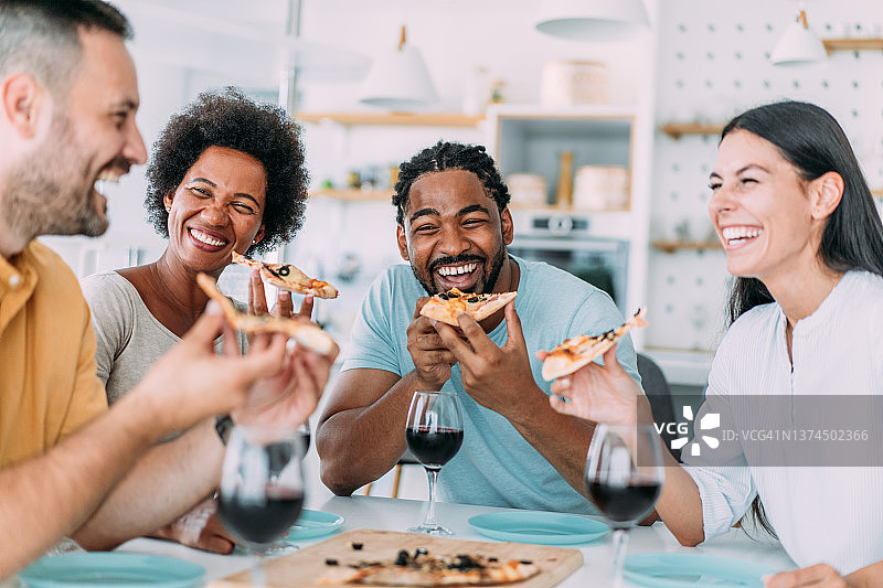 快乐的朋友们在家一起吃披萨和喝葡萄酒图片素材