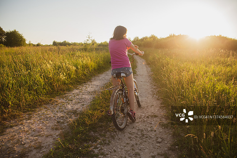 在田野里骑旧自行车的少女图片素材