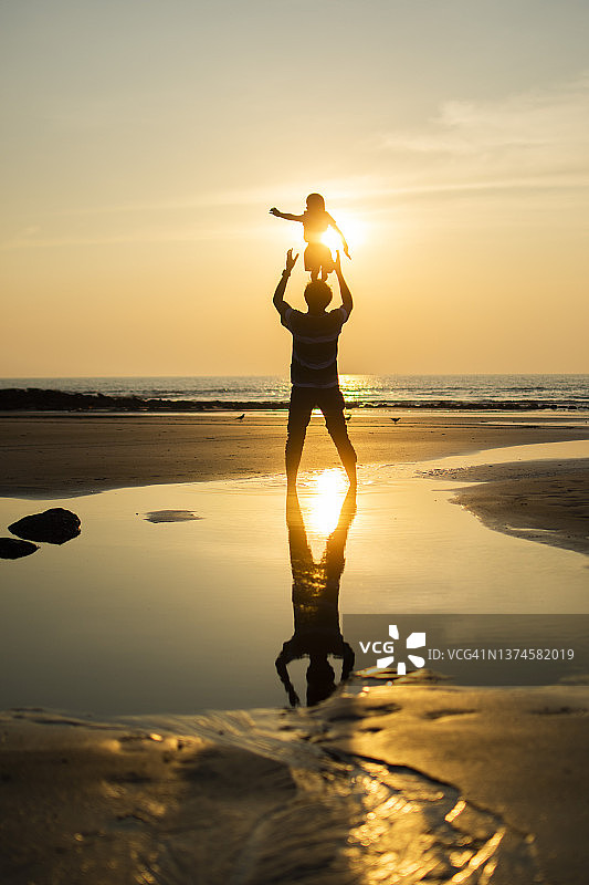 在海滩上把儿子抛向空中的父亲图片素材