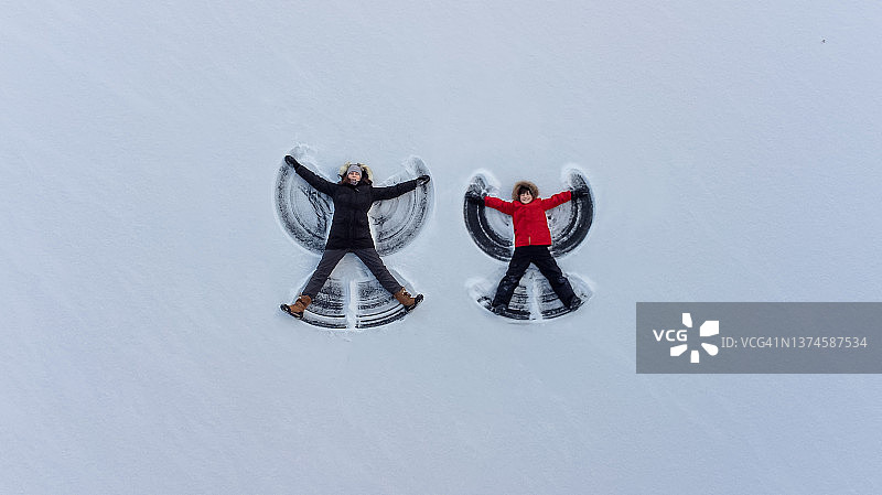 俯视：成人和儿童一起做雪天使图片素材