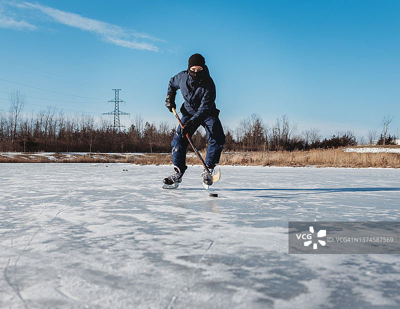 在加拿大冬季结冰的池塘上打冰球的青少年男孩图片素材