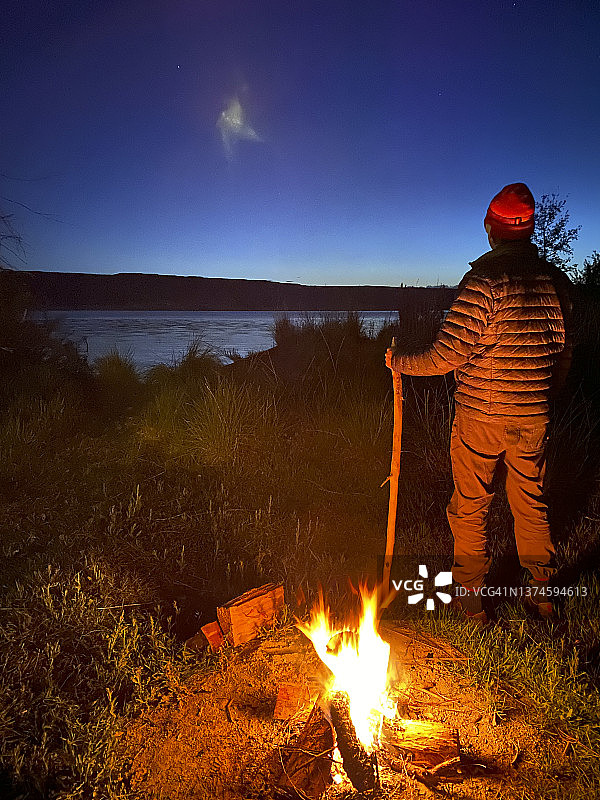 男人站在夜晚闪闪发光的篝火旁图片素材
