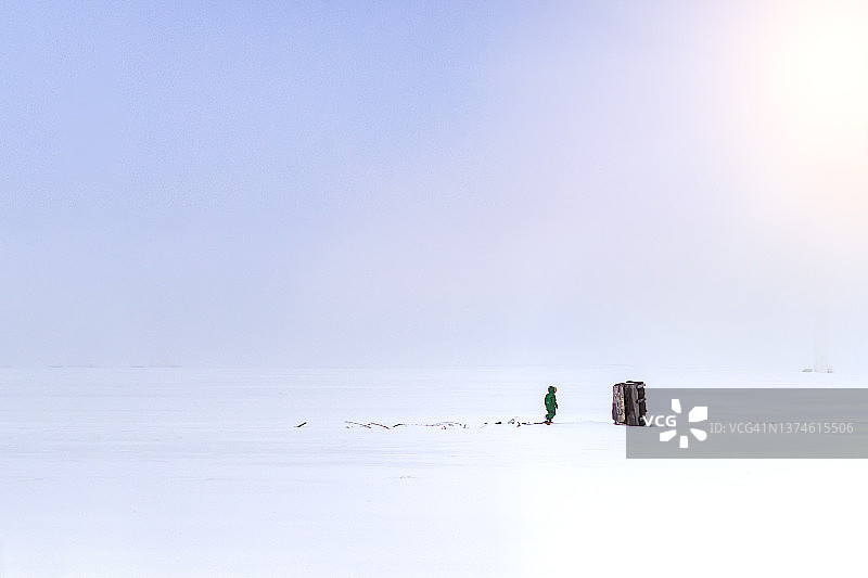 在爱荷华州风力发电场雪地中行走的一个男孩图片素材