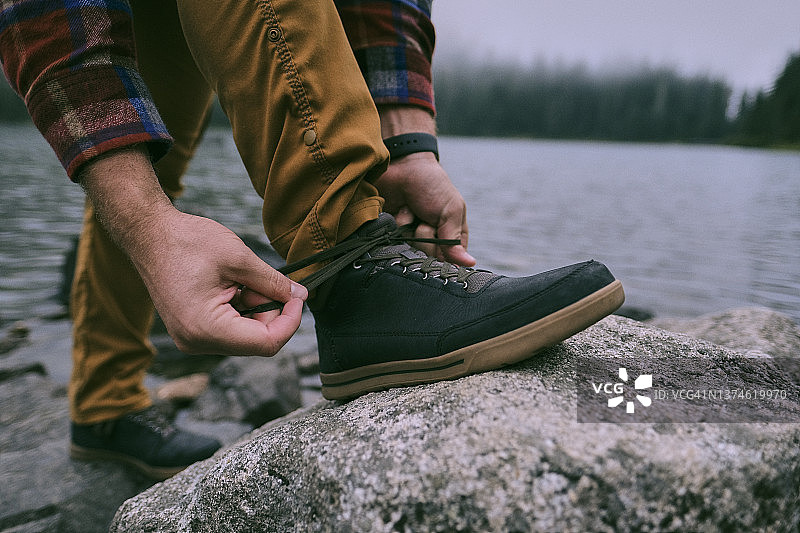 一个穿着法兰绒的男人用巨石系鞋带图片素材