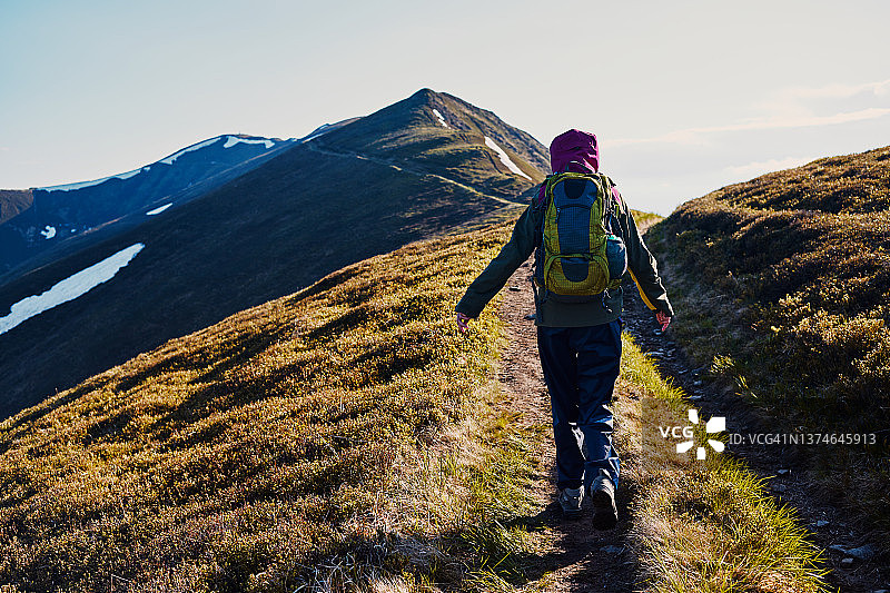 沿着山脉的山路行走的女人（后视图）图片素材