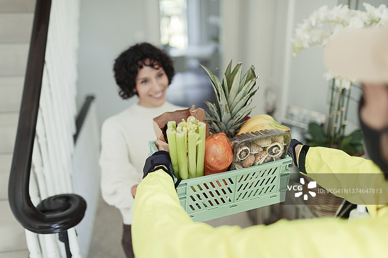 快递员送货上门，妇女在家接收食品杂货图片素材