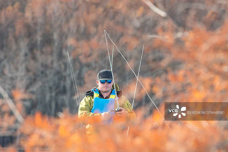 男人秋季在皮划艇上钓鱼图片素材