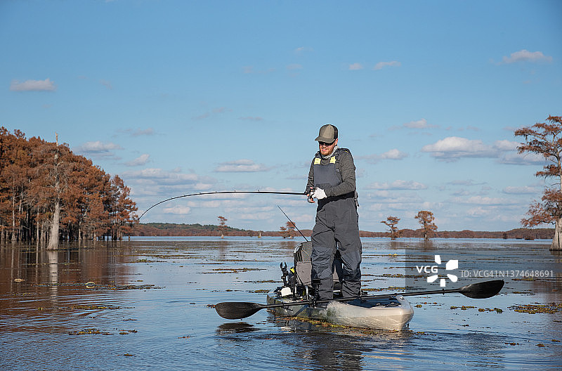 男人在皮划艇上钓鲈鱼图片素材
