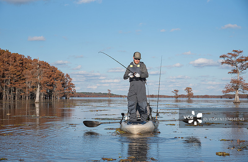 男人在皮划艇上钓鲈鱼图片素材