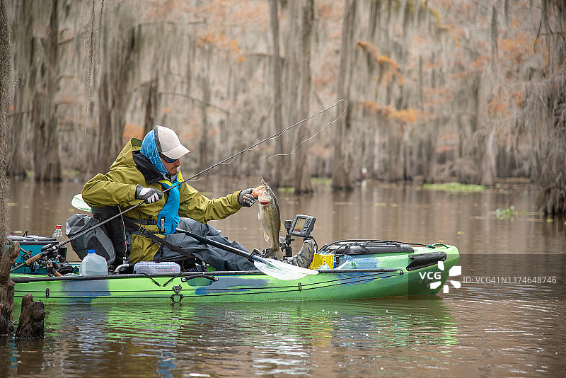 男人在皮划艇上钓鲈鱼图片素材