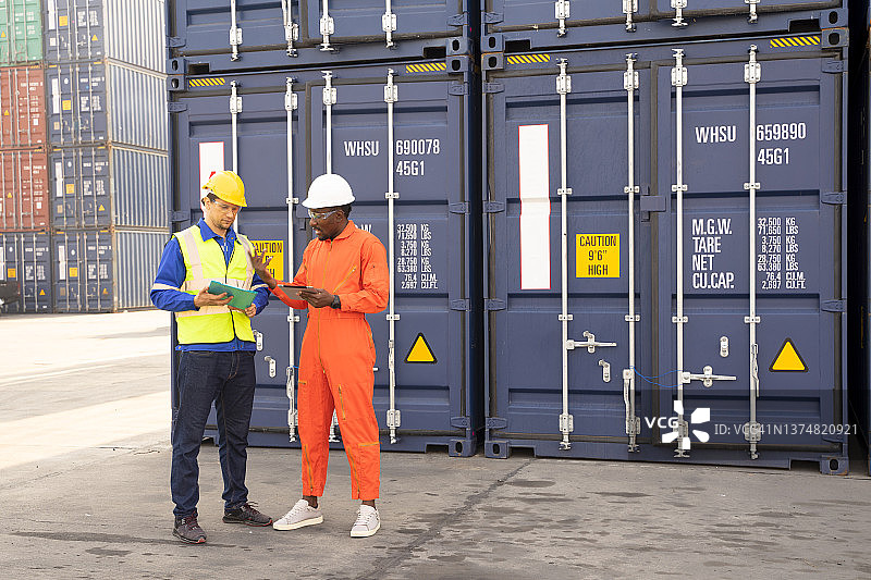 工程师们正在监督仓库内装有集装箱的货物的运输。集装箱在进出口业务和物流中图片素材