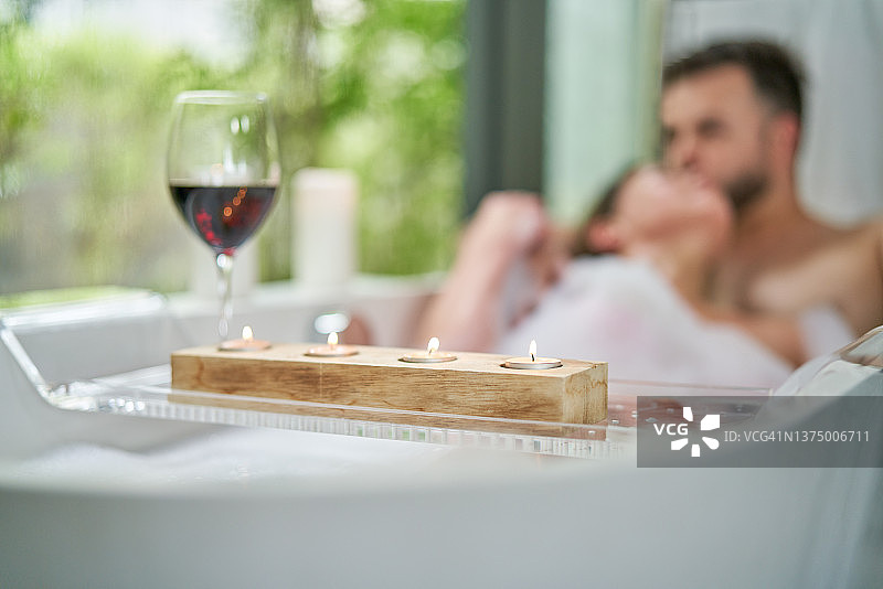 浪漫情侣在浴缸里享受泡泡浴和葡萄酒图片素材