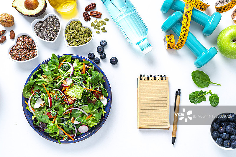 白色餐桌上的健康沙拉和笔记本图片素材