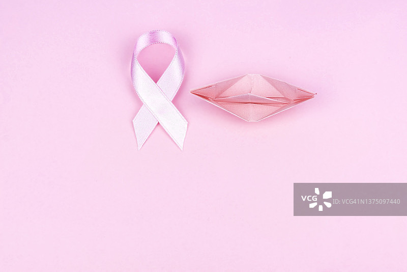 粉红色背景上的粉红色丝带和纸船图片素材
