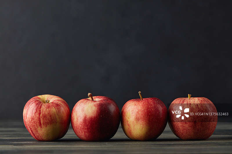 深色背景上排列在一起的苹果静物图片素材