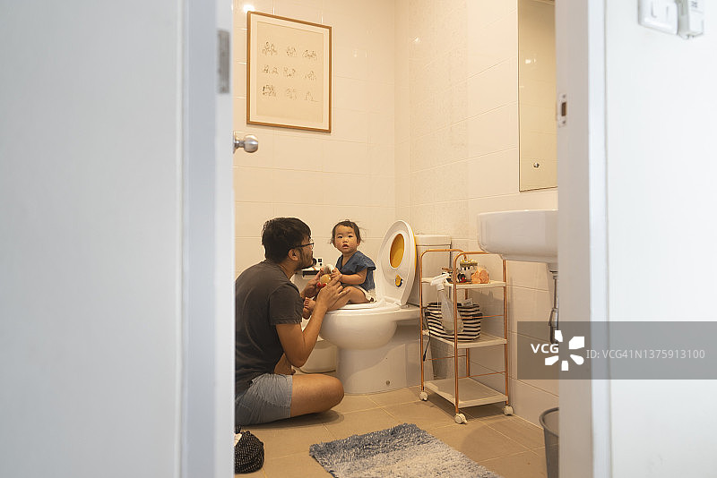 亚洲父亲鼓励女儿在家使用厕所的温馨时刻图片素材