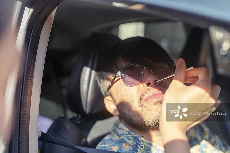 亚洲年轻人在驾车进行新冠病毒抗原检测图片素材