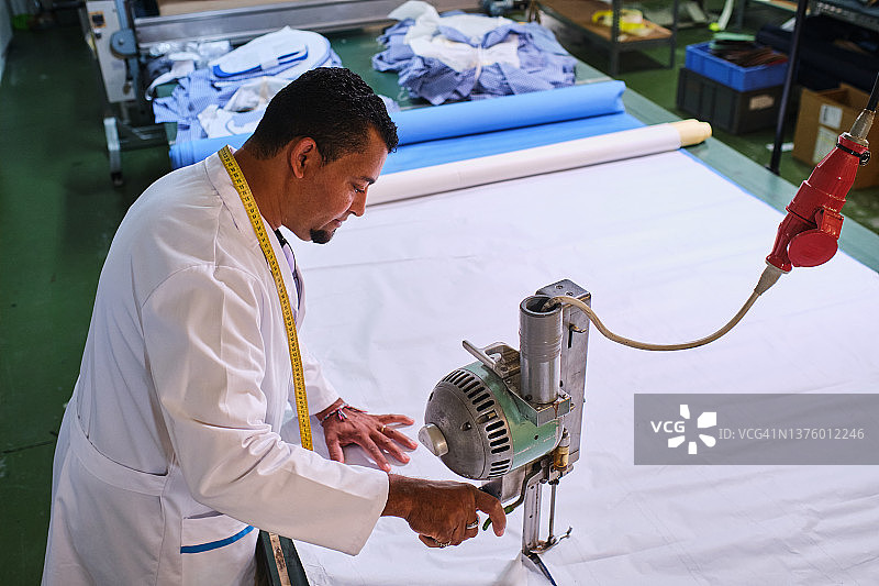 女裁缝在缝纫车间使用面料切割机图片素材