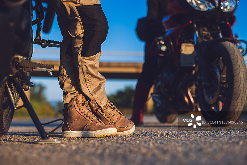 骑自行车的人在乡村道路日落时休息，靴子的特写图片素材