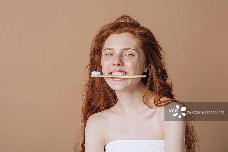 快乐的年轻女子拿着牙刷，看着镜头图片素材
