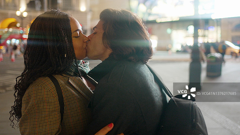 年轻情侣在城市街道的夜晚亲吻图片素材
