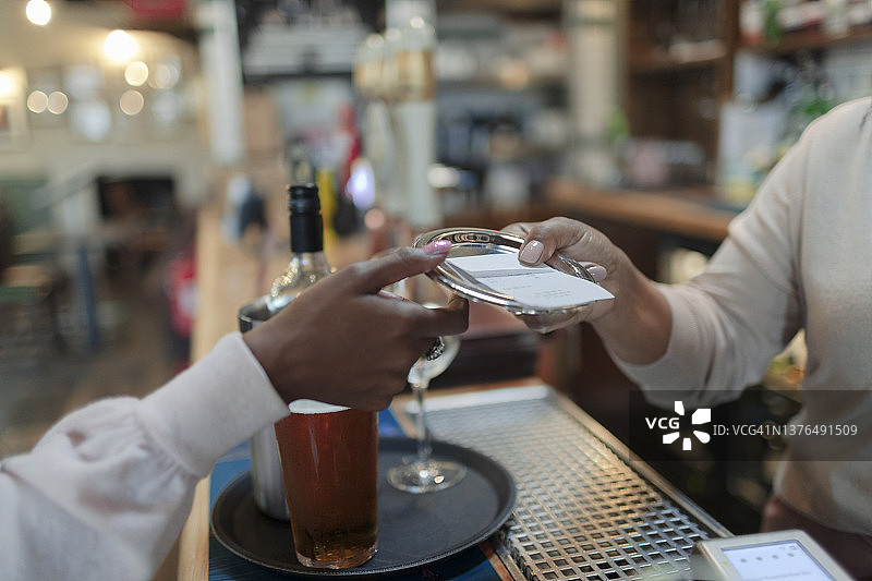 酒吧里，调酒师给顾客账单的特写图片素材
