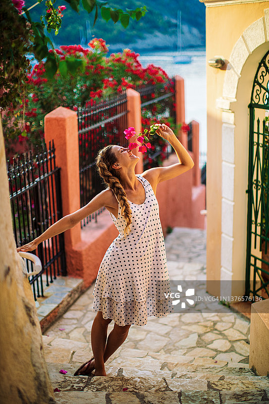 年轻女子在希腊岛屿的村庄街道上探索图片素材
