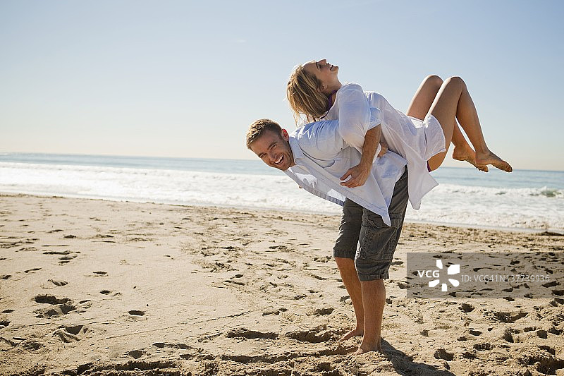 男人背着女人，背景是海图片素材