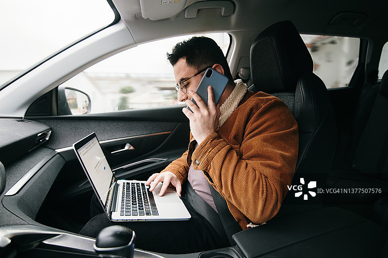 在行驶的汽车内工作的年轻男人图片素材
